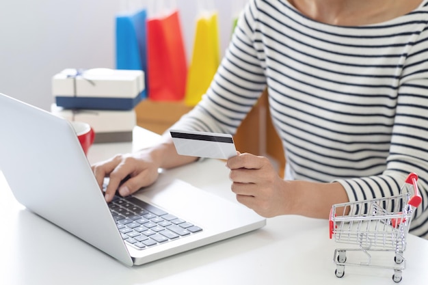 Foto sección media de una mujer comprando en línea usando una computadora portátil en la mesa