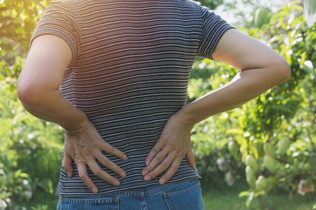 Foto sección media de una mujer con dolor de espalda mientras está de pie al aire libre