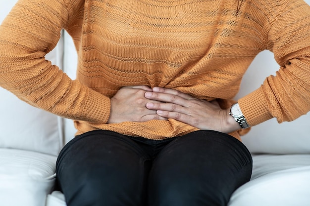 Foto sección media de una mujer con dolor de estómago sentada en casa