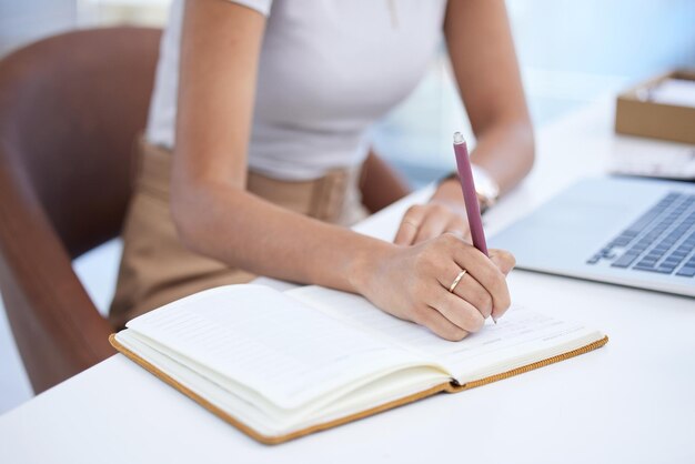 Foto sección media de una mujer escribiendo en un libro en la oficina