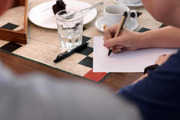 Sección media de una mujer escribiendo en papel en la mesa