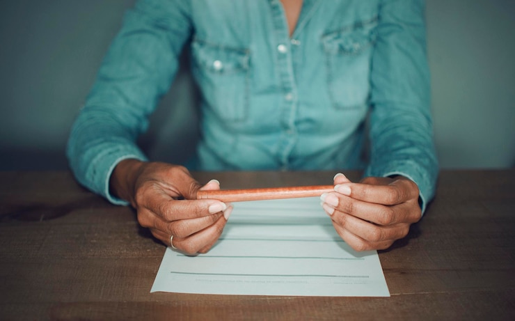 Foto sección media de una mujer escribiendo en papel mientras está sentada en la mesa