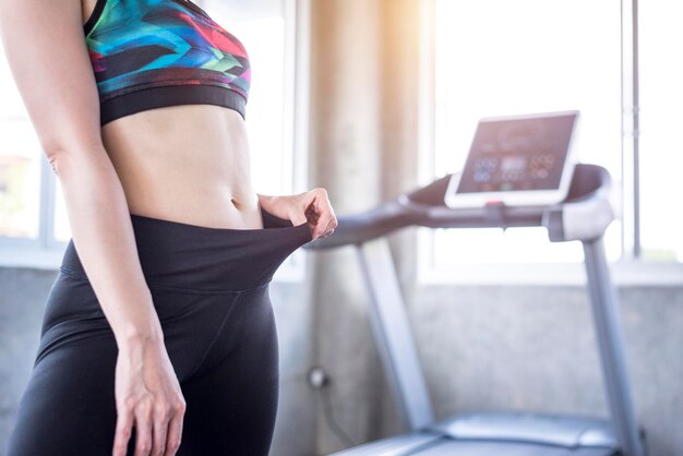Sección media de una mujer estirando pantalones en el gimnasio