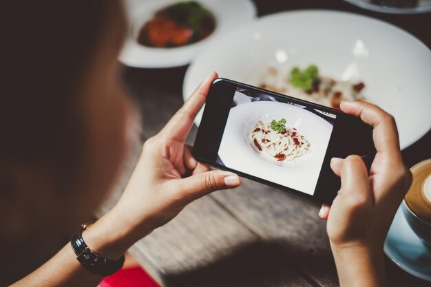 Foto sección media de una mujer fotografiando con teléfono móvil