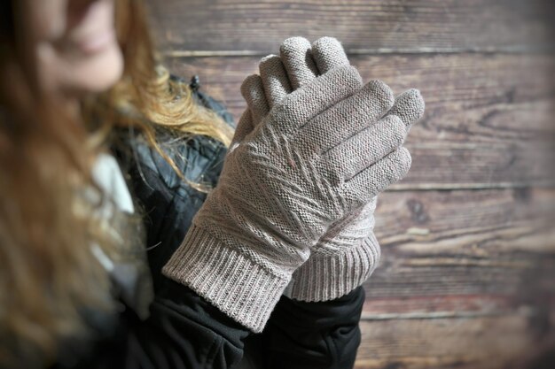 Sección media de una mujer con guante de lana contra una pared de madera