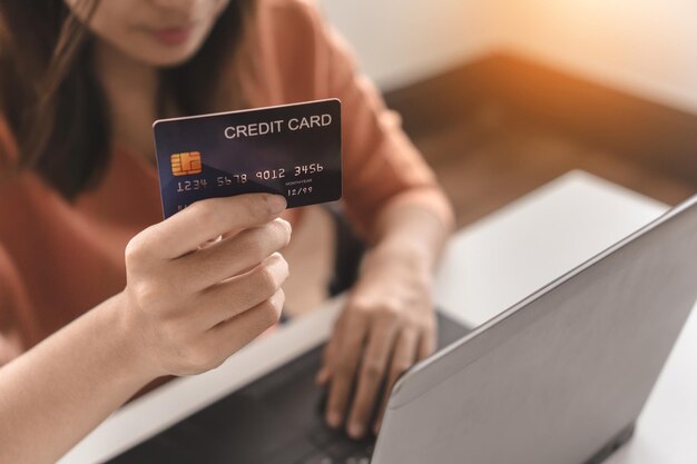 Sección media de una mujer haciendo compras en línea a través de una computadora portátil en casa