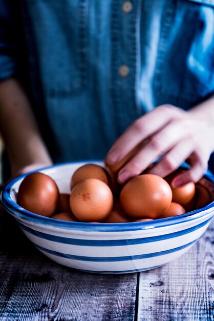 Foto sección media de una mujer con huevos marrones en la mesa