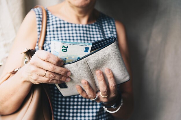 Foto sección media de una mujer insertando dinero del bolso