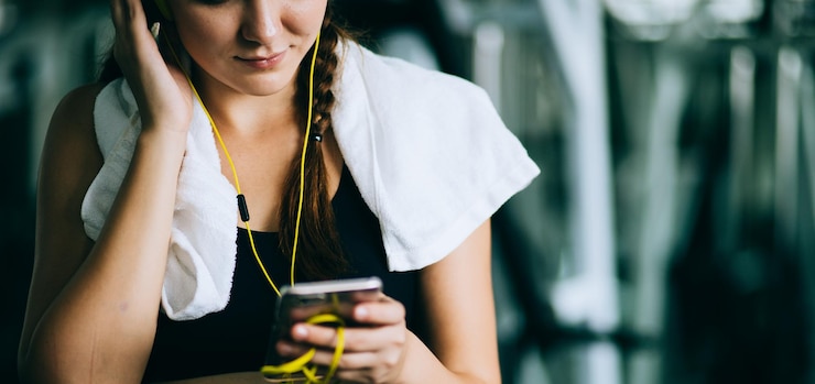 Foto sección media de una mujer joven escuchando música en el gimnasio