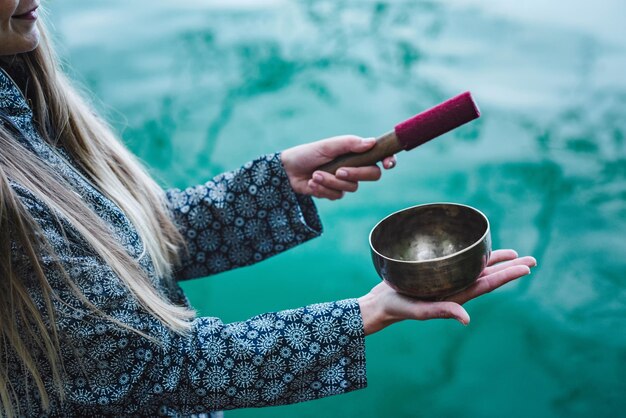 Foto sección media de una mujer joven sosteniendo un cuenco sobre el lago