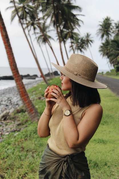 Foto sección media de una mujer joven sosteniendo un sombrero mientras está de pie en tierra