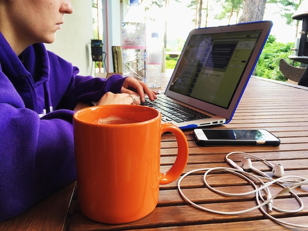 Sección media de una mujer joven usando una computadora portátil en la mesa