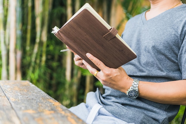 Foto sección media de una mujer leyendo un libro mientras está sentada en la madera