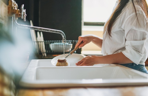 Foto sección media de una mujer limpiando platos en casa