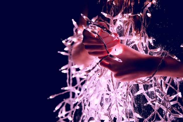 Foto sección media de una mujer con luces de cuerda por la noche