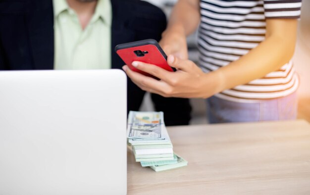 Foto sección media de una mujer mostrando un teléfono inteligente a un hombre de negocios usando una computadora portátil