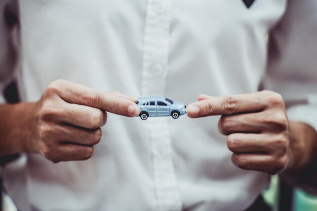 Sección media de una mujer de negocios con un coche de juguete