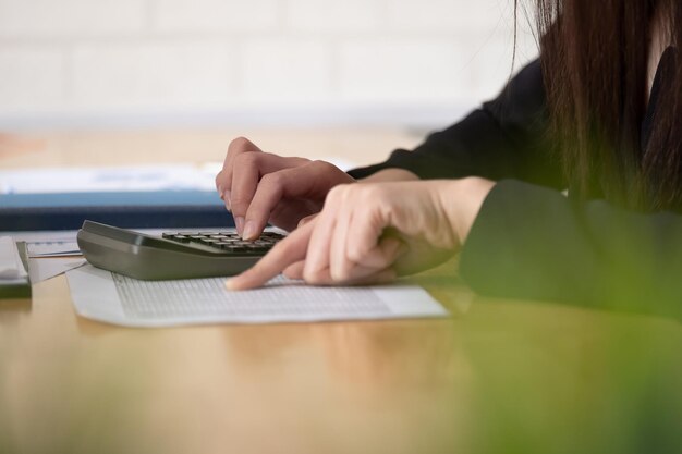 Foto sección media de una mujer de negocios que usa una calculadora en la mesa de la oficina