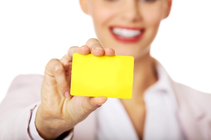Foto sección media de una mujer de negocios sosteniendo una tarjeta amarilla contra un fondo blanco