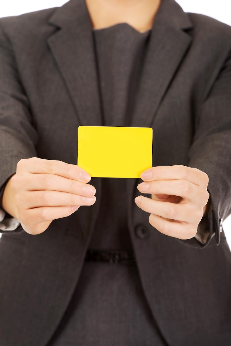 Foto sección media de una mujer de negocios sosteniendo una tarjeta amarilla contra un fondo blanco