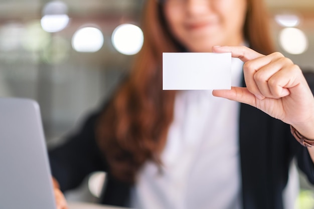 Sección media de una mujer de negocios con una tarjeta de visita en la oficina