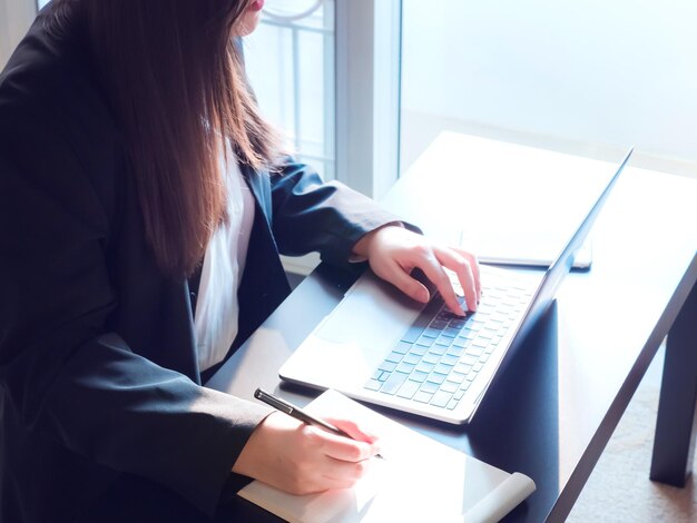 Sección media de una mujer de negocios usando una computadora portátil en el escritorio de la oficina