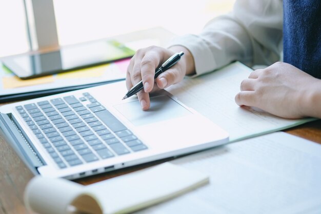 Sección media de una mujer de negocios usando una computadora portátil en el escritorio