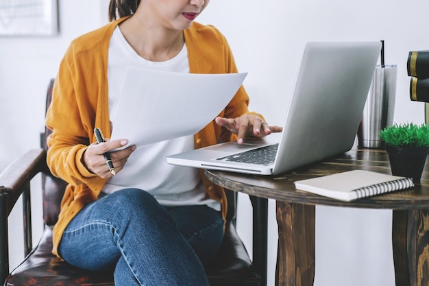 Sección media de una mujer de negocios usando una computadora portátil mientras trabaja en la oficina