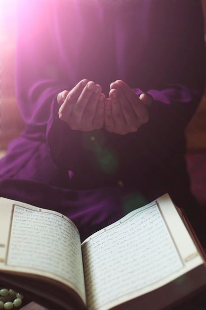 Foto sección media de una mujer orando sobre el corán