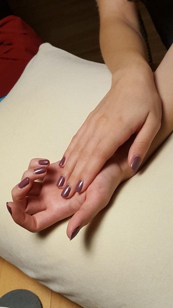 Sección media de una mujer que muestra esmalte de uñas en la almohada