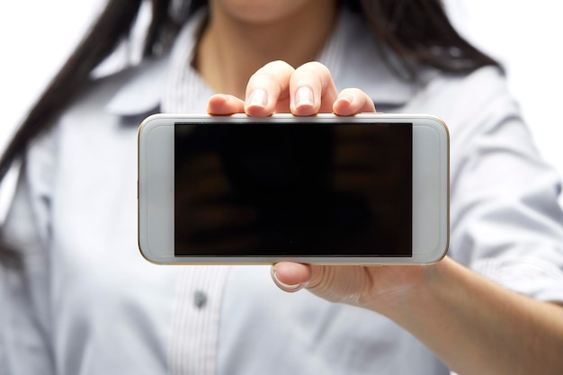 Foto sección media de una mujer que muestra un teléfono inteligente con una pantalla en blanco