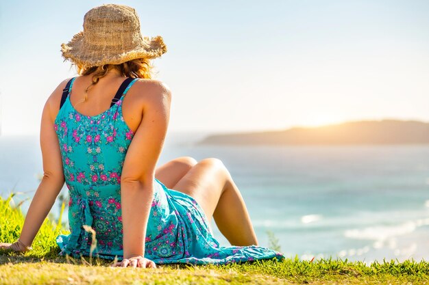 Foto sección media de una mujer sentada junto al mar contra el cielo