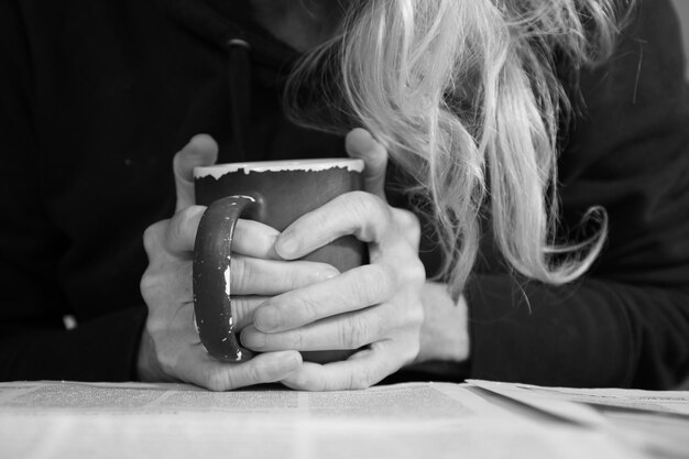 Foto sección media de una mujer sentada sosteniendo una taza de café