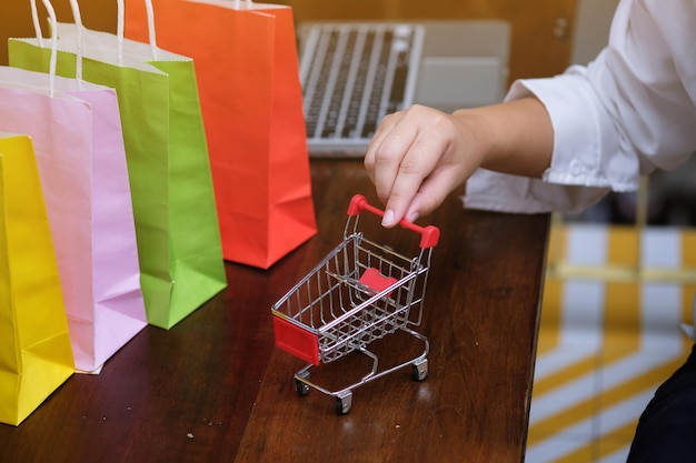 Foto sección media de una mujer sosteniendo un carrito de compras de juguetes en la mesa