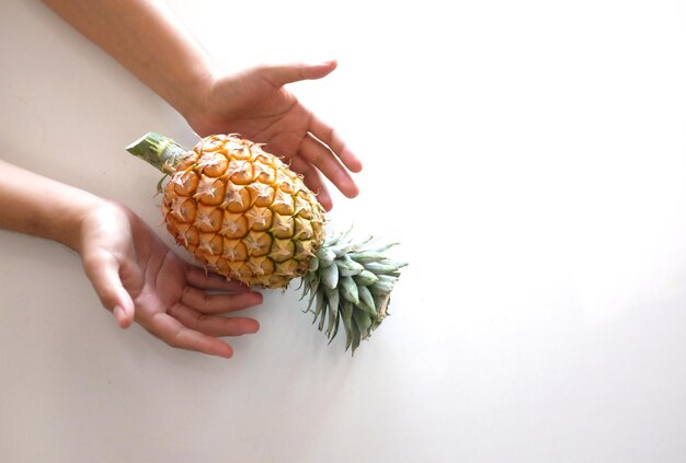 Foto sección media de una mujer sosteniendo una fruta contra un fondo blanco