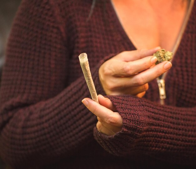 Foto sección media de una mujer sosteniendo un joint de marihuana