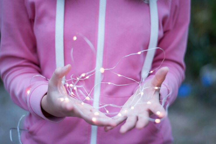 Foto sección media de una mujer sosteniendo luces de cuerda iluminadas