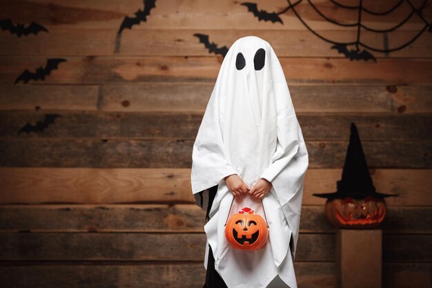 Foto sección media de una mujer sosteniendo un paraguas contra una pared de madera durante halloween