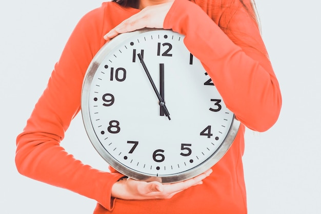 Sección media de una mujer sosteniendo un reloj