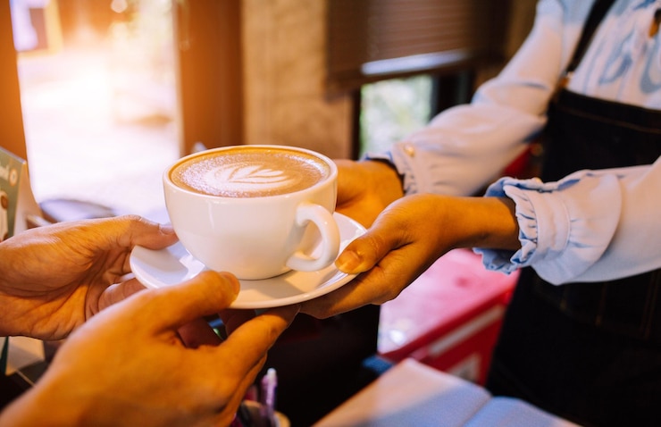 Foto sección media de una mujer sosteniendo una taza de café en una cafetería