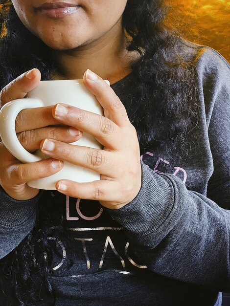 Foto sección media de una mujer sosteniendo una taza