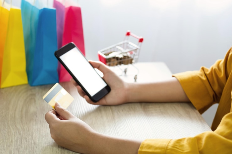 Foto sección media de una mujer con teléfono y tarjeta de crédito en la mesa