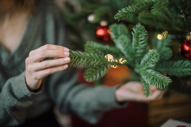 Sección media de una mujer tocando el árbol de Navidad en casa