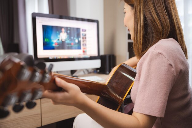 Sección media de una mujer tocando la guitarra en casa