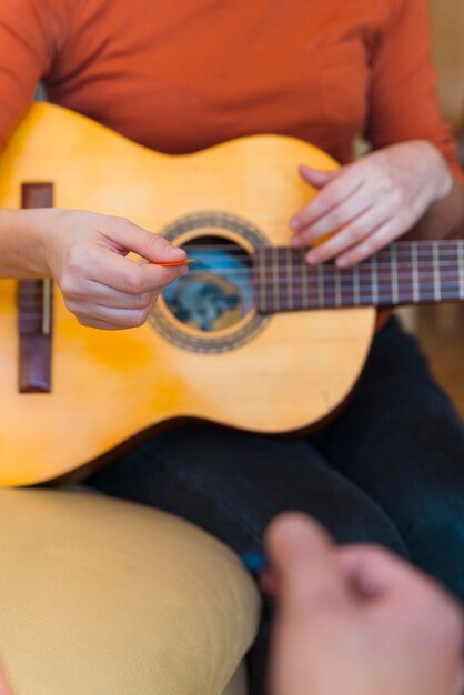 Sección media de una mujer tocando la guitarra en casa