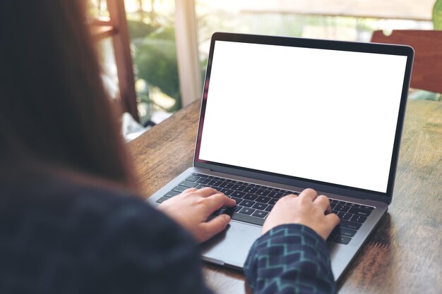 Sección media de una mujer usando una computadora portátil en la mesa en un café