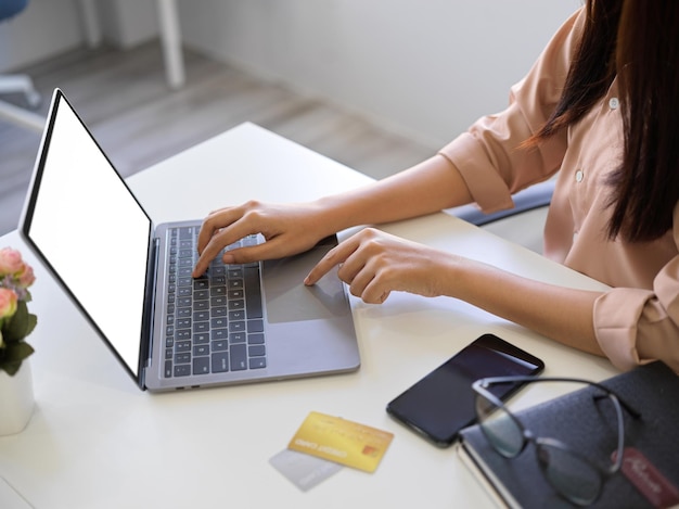 Sección media de una mujer usando una computadora portátil en la mesa