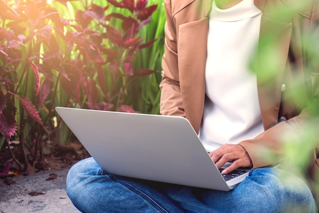 Sección media de una mujer usando una computadora portátil mientras está sentada en el campo