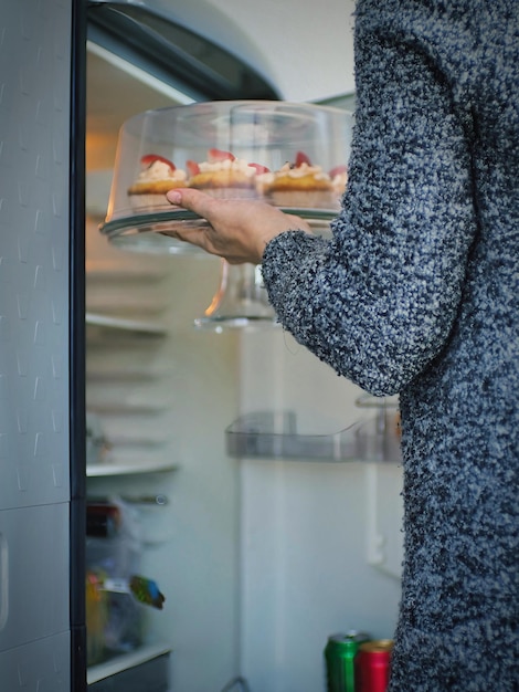 Sección media de una mujer usando un refrigerador