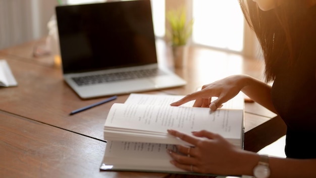 Sección media de una mujer usando un teléfono inteligente en la mesa